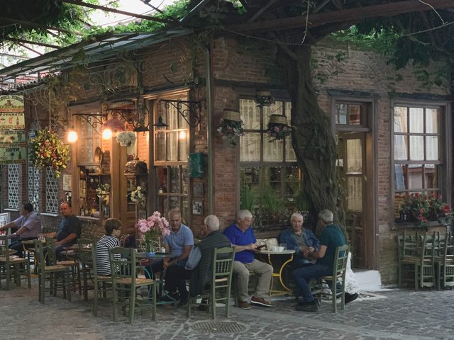 Kafé under träden vid en kullerstensgränd i Agiasos