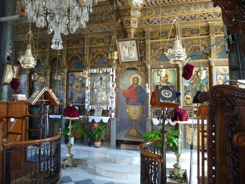 Interiören i Panagia Glykofilousa med förgylld ikonostas, ikoner och kristallkronor
