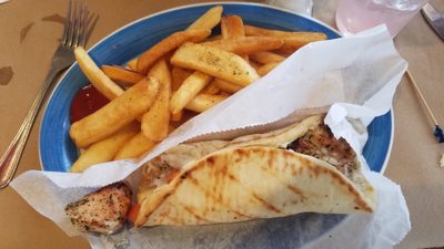 Kycklingsouvlaki i pitabröd med tomat och sås, serverad med pommes frites